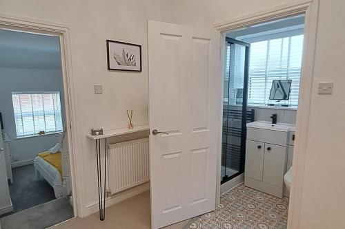 ein Badezimmer mit einer weißen Tür und einem Waschbecken in der Unterkunft The Tanners Cottage in Hathern