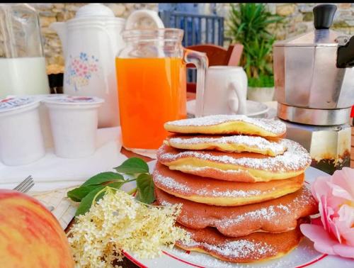 a stack of pancakes on a plate with orange juice at Agriturismo La Greciola in Gabbiana