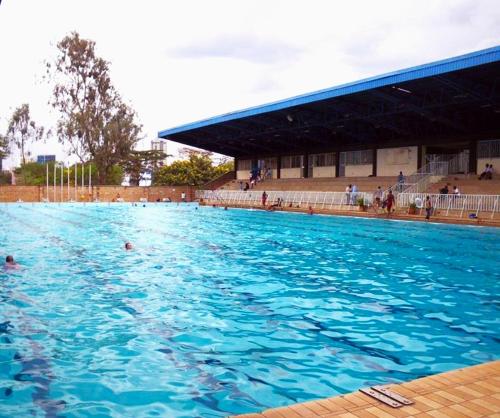 una grande piscina di acqua blu con persone all'interno di Serene Hills Home a Nairobi