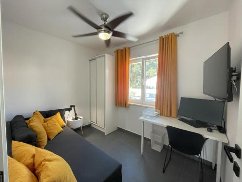 a living room with a couch and a desk with a television at Valkane Beach Apartments in Pula