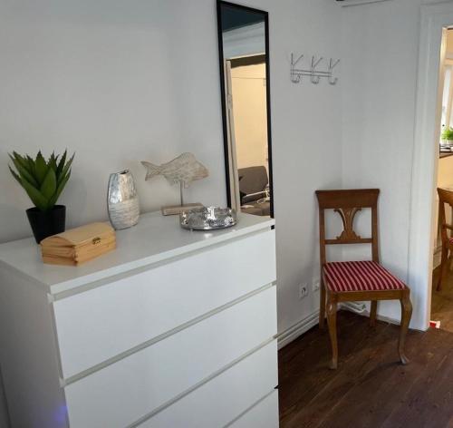 een kamer met een dressoir met een spiegel en een stoel bij Matrosenkoje in Flensburg