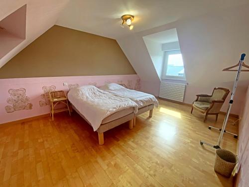 Schlafzimmer im Dachgeschoss mit einem Bett und 2 Stühlen in der Unterkunft RÉF 466 - PLOEMEUR maison avec piscine 4 chambres in Ploemeur