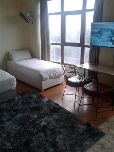 a room with a bed and a desk and a table at Bed and breakfast studio apartments in Nairobi