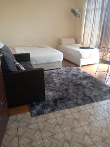 a living room with two beds and a rug at Bed and breakfast studio apartments in Nairobi