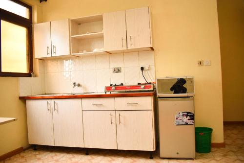 a kitchen with white cabinets and a refrigerator at Bed and breakfast studio apartments in Nairobi