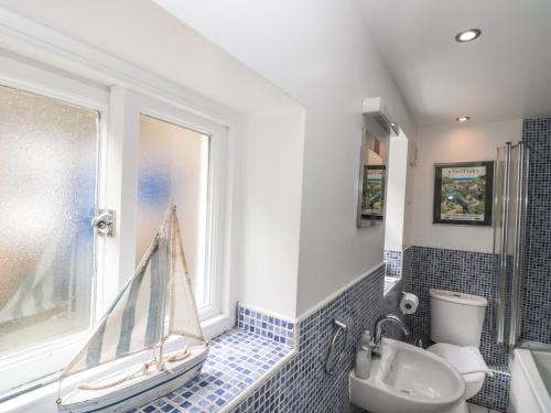 ein Bad mit einem Waschbecken, einem WC und einem Fenster in der Unterkunft Grimes Cottage in Staithes