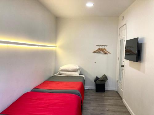 a small bedroom with a red bed and a tv at Modern GuestHouse Ironbound Newark with KITCHEN-FastTrainToNYC-OneStopToAirport in Newark