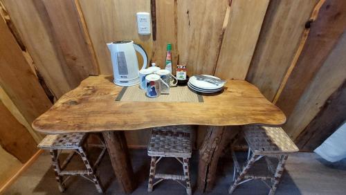 a wooden table with a coffee maker and two stools at Cabañas & Habitaciones Del Alto in Hornopiren