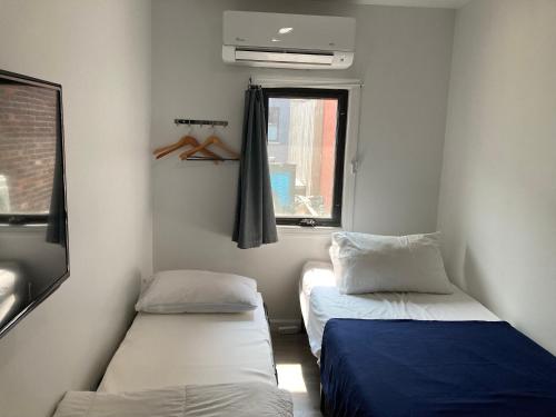 a small room with two beds and a window at Modern GuestHouse Ironbound Newark with KITCHEN-FastTrainToNYC-OneStopToAirport in Newark