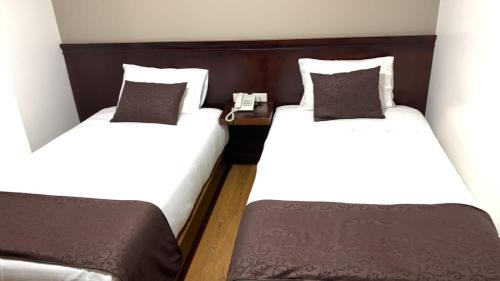 two twin beds in a room with a phone between them at HOSTAL CAMIL in Loja