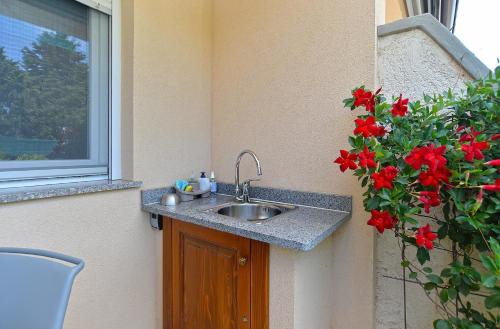 um lavatório no canto de uma casa com flores vermelhas em Ferienhaus für 4 Personen ca 37 qm in Peroj, Istrien Istrische Riviera em Peroj