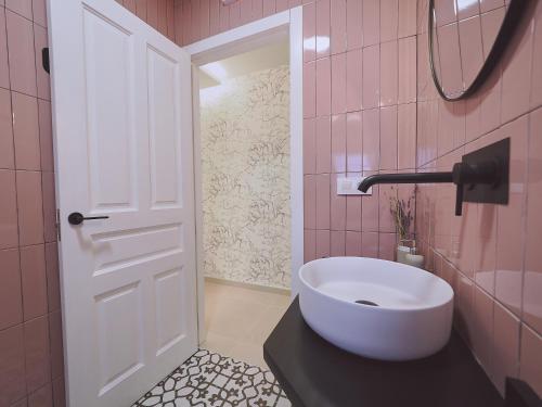 a bathroom with a white sink and pink tiles at Hostal Casa Maria in Batán del Puerto