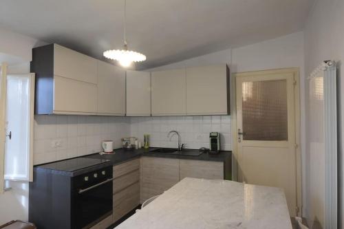 a kitchen with white cabinets and a black counter top at grande appartamento in versilia in Camaiore