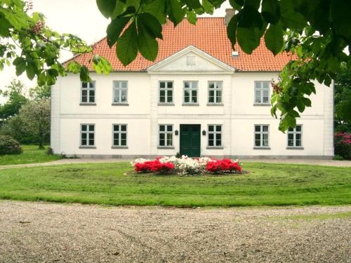 a large white house with red flowers in the yard at Oase Friedensthal in Friedenstal