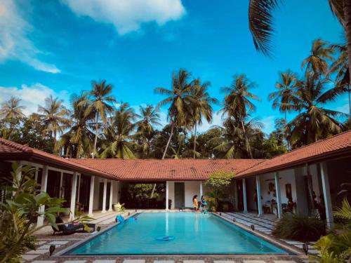 a villa with a swimming pool and palm trees at VILLA BLUE LOTOUS in Gampaha