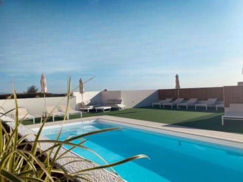 a swimming pool with chaises and chairs in front of a building at La Maison Du Belvedere in Saint-Cyprien