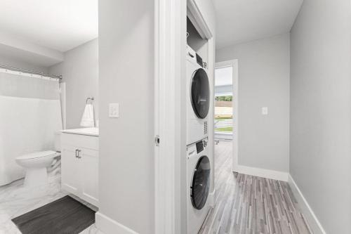 a white bathroom with two washers and a toilet at Cozy Two-Bedroom Two-Bathroom Stay in the Heart of Rochester Hills in Rochester Hills