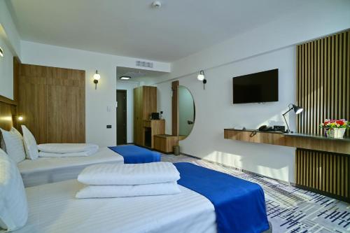 Habitación de hotel con 2 camas y TV en Hotel Sir Royal, en Bucarest