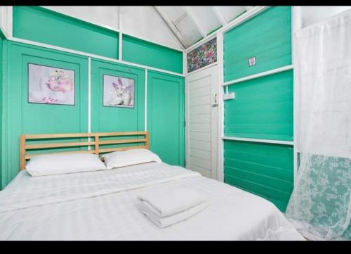 - une chambre avec des murs verts et un grand lit dans l'établissement Hillside cottage chalet studio, à Tanah Rata