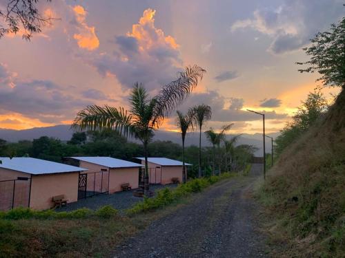 a dirt road with buildings and palm trees at sunset at Flor del Monte in Sopetran