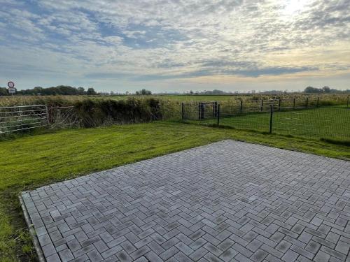 a brick walkway in the middle of a field at G1 Eingezäuntes Haus mit Kamin in Eckwarderhörne in Großwürden