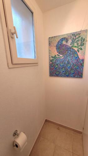 une salle de bain avec un distributeur de papier toilette et un tableau dans l'établissement Seaview house, close Cannes, pool, garden. garage, à Théoule-sur-Mer