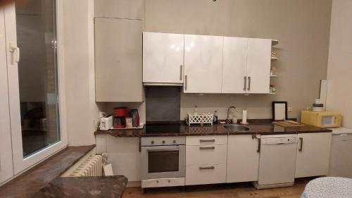 - une cuisine avec des placards blancs et un évier dans l'établissement Antique appartement au centre d'Andenne, à Andenne