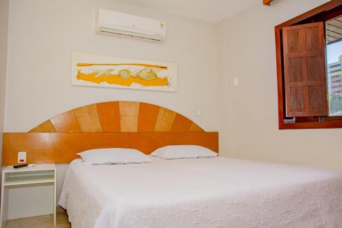 a bedroom with a white bed with a wooden headboard at Garbos Soleil Hotel in Natal