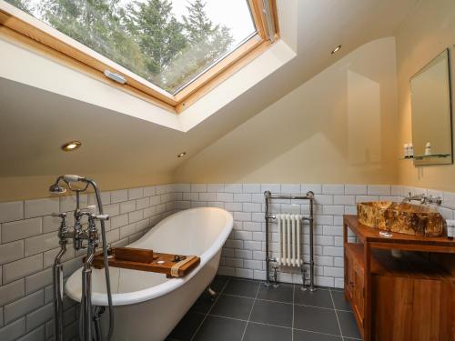 uma casa de banho com uma grande banheira e uma clarabóia em Coventina em Staines upon Thames