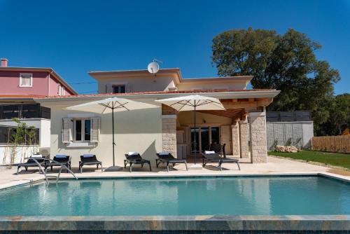 una casa con piscina con sillas y sombrillas en Ferienhaus mit Privatpool für 6 Personen ca 150 qm in Vinež, Istrien Bucht von Raša en Vinež