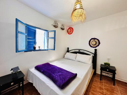 a bedroom with a bed with a purple blanket on it at Azoul Surf Hostel Taghazout in Taghazout