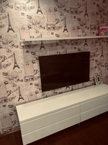 a flat screen tv on a wall with drawings on it at Apartman Centar in Brčko