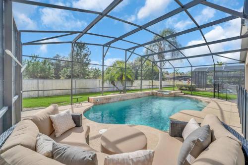 a glass house with a couch and a swimming pool at Enjoyable 6BR Home Near Disney in Orlando