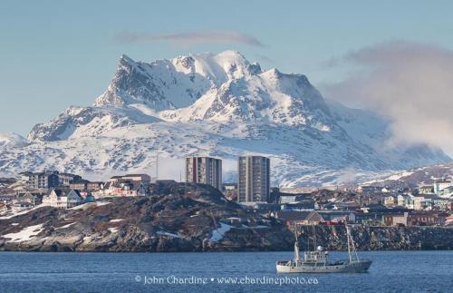 un barco en el agua frente a una montaña en Hotel Aurora Apartments, en Nuuk