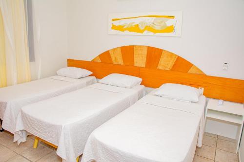 two beds in a room with white sheets at Garbos Soleil Hotel in Natal