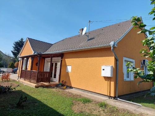 uma casa amarela com um alpendre e um quintal em Schönes Ferienhaus mit Pool in ruhiger Lage em Balatonszentgyörgy