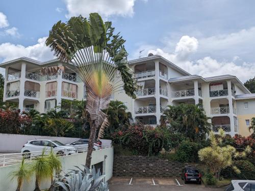 a large white building with a palm tree in front of it at Studio 26m 2 pas Marina du Marin climatisé + parking in Le Marin