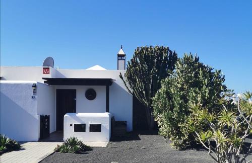 een wit gebouw met een poort en enkele bomen bij Sich wie zu Hause fühlen in Playa Blanca