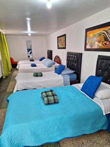 Habitación con 4 camas y almohadas azules. en HOTEL GALICIA PLAZA, en Manizales