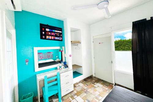 een kamer met een blauwe muur, een bureau en een tv bij Yabanhi Hostel in Oaxaca City