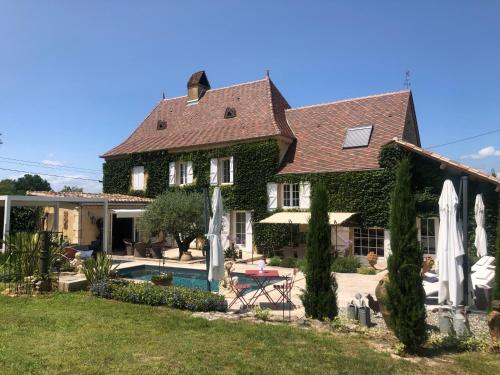 une maison avec une piscine et une cour avec des parasols dans l'établissement Studio indépendant, à Anglars-Nozac