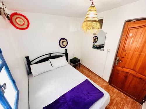 a bedroom with a bed and a wooden door at Azoul Surf Hostel Taghazout in Taghazout