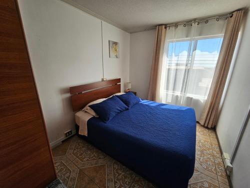 1 dormitorio con cama con sábanas azules y ventana en Playa Blanca B&B Antofagasta, en Antofagasta