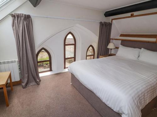 雷文格拉斯的住宿－Old School Muncaster House，一间卧室设有一张大床和两个窗户。