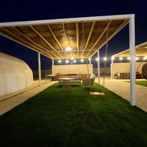 a pavilion with a table and chairs on the grass at Desert Breeze in Al Ḩamrānīyah