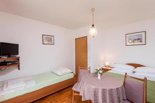 Cette chambre comprend 2 lits, une table et une télévision. dans l'établissement Ferienwohnung für 2 Personen ca 30 qm in Viganj, Dalmatien Süddalmatien, à Viganj
