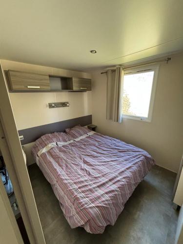 1 dormitorio con cama y ventana en Mobilhome, en Névian
