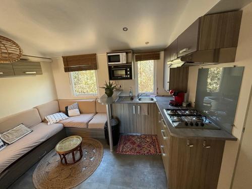 a kitchen and a living room with a couch in a caravan at Mobilhome in Névian