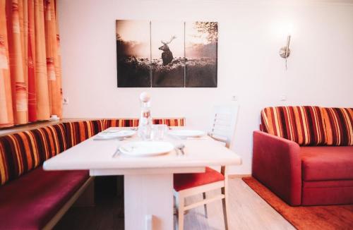 een eetkamer met een witte tafel en een rode bank bij Ferienwohnung in Bach mit Garten und Grill - b61639 in Bach