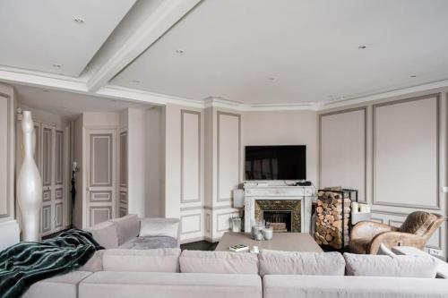 un salon avec un canapé blanc et une cheminée dans l'établissement Resplendent Haussmann Design 100m2 - 2 BR, à Paris